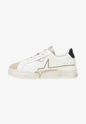 Baskets basses blanches avec bout en daim beige, détail étoile dorée sur le côté, languette dorée pailletée et languette talonnière noire.