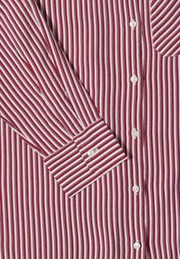 Chemise à manches longues à rayures verticales blanches et rouges avec poignets à boutons et boutons blancs au centre devant.