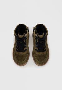 Bottines en suede vert avec des lacets noirs, finition texturée et semelle en caoutchouc. Des zips latéraux facilitent l'enfilage.