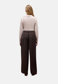 Jasno beżowy sweter z kołnierzykiem, zestawiony z brązowymi spodniami o wysokim stanie i szerokich nogawkach, z tylnymi kieszeniami. Gładka tekstura, nowoczesny design.