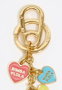 Gold-tone metal keychain featuring a circular clip and three colorful heart charms in pink, blue, and green with embossed text.