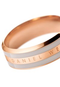 Vihreä kultainen sormus, jossa on vuorotellen valkoisia ja harmaita emaliraitoja, ja jossa on kaiverrus "DANIEL WEL" sileällä, kiillotetulla pinnalla.