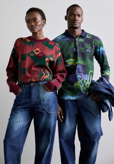 Knit sweater in red with green and orange abstract patterns, paired with blue denim pants featuring a diamond texture and contrasting seams.
