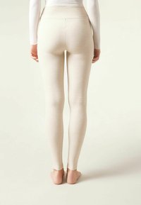 Cremefarvede ribbede leggings med høj talje, tætsiddende silhuet og glat tekstur, der strækker sig til barfødder.
