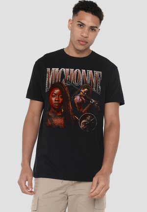 Young man wearing black t-shirt featuring three graphic images of Michonne holding a katana and her name in large letters above.