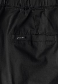 Svarta tygshorts med en bakficka som har en svart etikett och kontrasterande sömmar för extra detalj och textur.