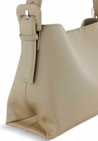 Borsa a spalla in pelle beige con una forma strutturata, dotata di una larga tracolla con una fibbia argentata e una texture liscia. Gli accenti sono minimi.