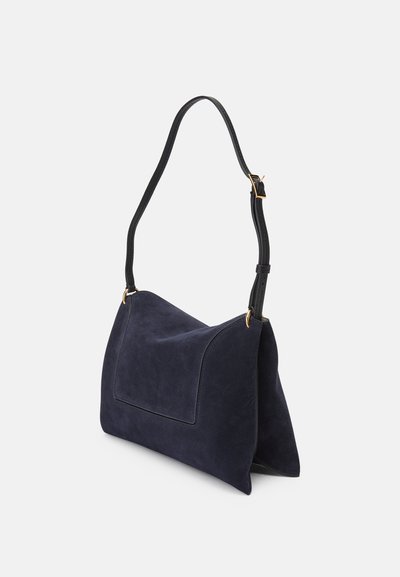 Bolsa de ombro em camurça azul-marinho com um design estruturado, alça preta única, acessórios em dourado e um bolso de patch na frente.
