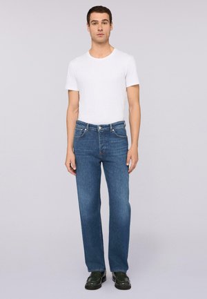 Blauwe denim jeans met een rechte pasvorm, voorzien van vijf zakken en contrasterend stiksels. Gepaarde met een eenvoudig wit T-shirt met ronde hals en zwarte schoenen.