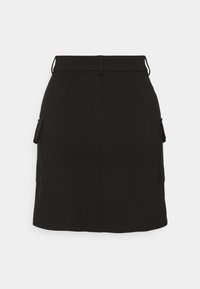 Černá sukně s přiléhavým střihem, dvěma bočními kapsami a hladkým textilním vzhledem. Má pás a rovný lem.