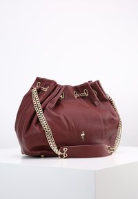Burgundowa skórzana torba z złotymi łańcuszkami, zebranym wzorem i metalicznym akcentem w postaci logo. Teksturowana powierzchnia nadaje jej charakterystyczny wygląd.