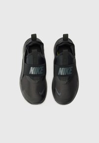 Baskets noires Nike à enfiler avec une tige texturée, une sangle élastique avec logo, un design de coques de orteils et des tirettes pour un enfilage facile.