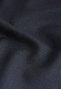 Tissu tissé de couleur bleu marine foncé, avec une texture visible et de douces plis créant des ombres et des reflets délicats.