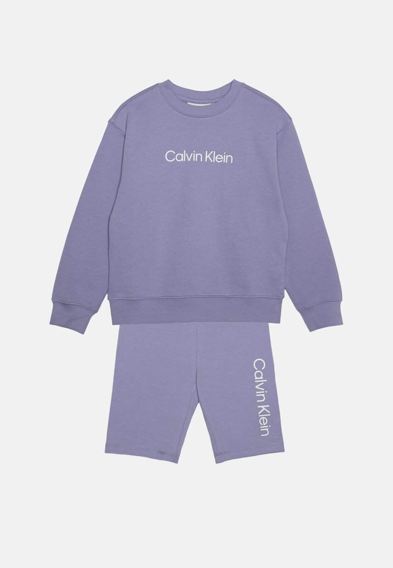 Completo in cotone viola composto da felpa e pantaloni corti abbinati. La felpa ha girocollo e il logo "Calvin Klein". I pantaloni corti presentano il logo sul lato.
