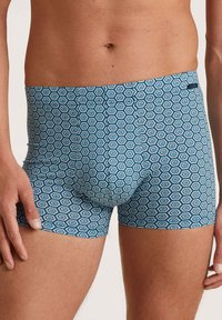 Blauwe boxer shorts met een hexagonaal patroon in afwisselend blauwe en witte kleuren, gemaakt van een gladde, rekbare stof.