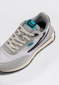 Sneaker grigio chiaro con una combinazione di materiali in suede e mesh. Presenta dettagli neri, intersuola crema e logo di marca turchese.