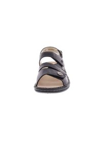 Sandal in pelle nera con tomaia chiusa, tre cinturini orizzontali, un bottone decorativo e una soletta interna color beige. Suola in gomma piatta.