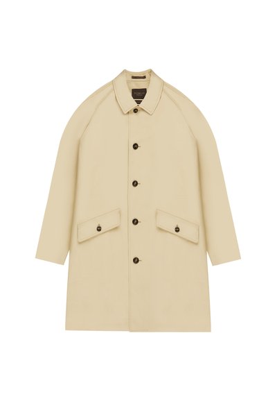 Manteau beige à longueur genou avec un col, de grandes poches avant et des boutons foncés. Présente des manches raglan et une texture de tissu lisse.
