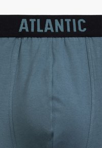 Jasnoniebieskie bokserki z miękkiego materiału, z czarnym elastycznym paskiem w talii z napisem "ATLANTIC" w jasnoniebieskim kolorze.