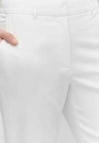 Witte op maat gemaakte broeken met een gladde textuur, slim fit, zijzakken en een schoon ontwerp van de tailleband. Geaccentueerd met subtiele stikdetails.