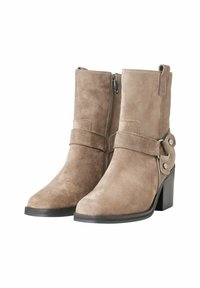 Tan suede ankle boots with a block heel, side zipper, and a decorative strap featuring metallic hardware accents. Smooth texture and rounded toe.