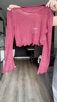 Langärmliges, kurzes Oberteil aus burgunderfarbenem Mesh-Stoff. Verfügt über einen runden Halsausschnitt und ausladende Ärmel mit einem gewellten Saum. Subtile Markenkennzeichnung sichtbar.
