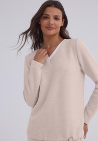 Jasnopiaste luźne bluzka z długim rękawem w serek, wykonana z miękkiego materiału, z kontrastowym białym wykończeniem przy dekolcie.