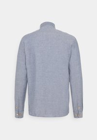 Camisa de manga larga azul claro hecha de tela texturizada, con un pequeño cuello y puños abotonados con botones de color dorado.