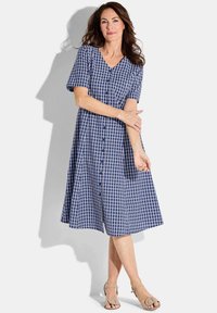 Abito a quadretti navy e bianco con maniche corte, scollatura a V e chiusura con bottoni. Gonna ampia, lunghezza ginocchio, realizzata in tessuto leggero.