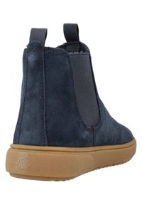 Tummansininen samettinen nilkkasaapas, jossa on joustavat sivupaneelit, pyöreä kärki ja kumipohja. Ominaisuuksina on litteä korko ja ompelupitsi sivuilla.