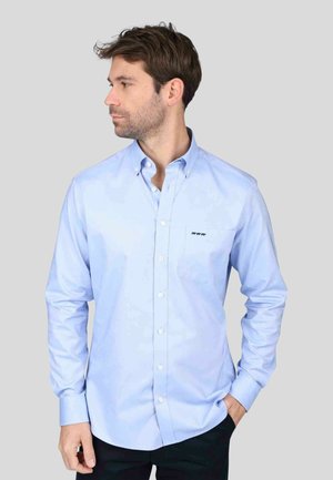 Chemise bleu clair à boutons en tissu lisse, dotée de manches longues, d'une poche poitrine et d'un petit logo brodé sur la poche.