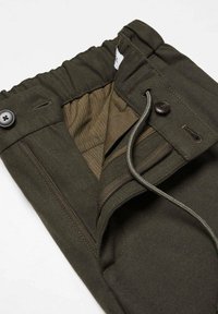 Pantalon vert foncé avec ceinture élastique, fermeture par bouton, braguette à glissière, cordon de serrage et doublure intérieure visible.