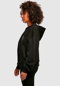 Felpa con cappuccio zip nera, dalla vestibilità comoda, con polsini a costine e un piccolo logo sul petto. Tessuto liscio, materiale morbido e cappuccio ampio.