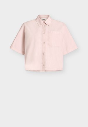 Lys rosa kortermet skjorte med knapper, spiss krage og én brystlomme, vist på en ensfarget lys grå bakgrunn.