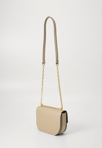 Borsa a tracolla in pelle beige con una forma curvata, tracolla in catena dorata e dettagli di cucitura a contrasto lungo i bordi.