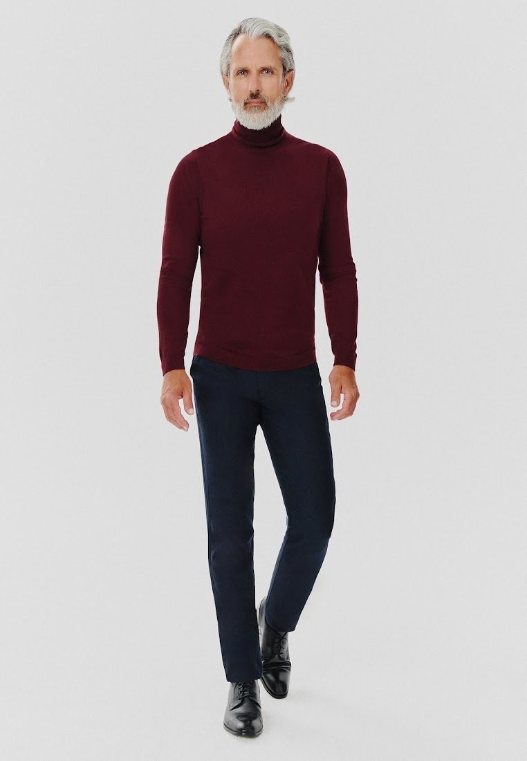 Bordowy sweter z golfem, dopasowany krój, zestawiony z ciemnoniebieskimi spodniami i czarnymi sznurowanymi butami, tworząc elegancki, profesjonalny wygląd.