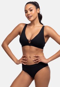 Melnas ribotas bikini tops ar platām siksnām un atslēgas caurumu centrā, apvienots ar augstu vidukli melnām ribotām apakšdaļām.