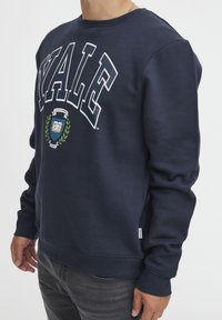 Sweatshirt blu navy con testo bianco "YALE", scollo rotondo, maniche lunghe e logo a scudo con vegetazione al centro. Tessuto morbido.