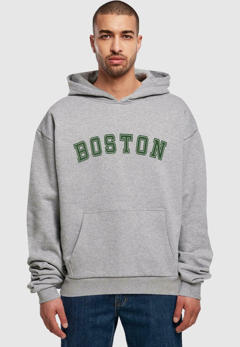 Grå hettegenser med "BOSTON" i mørkegrønn skrift. Har en frontlomme og ribbestrikket nederkant. Stoffet ser mykt ut med en avslappet passform.
