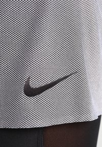 Tela deportiva de Nike con textura tejida en blanco y negro, con un distintivo logo de la marca en negro.