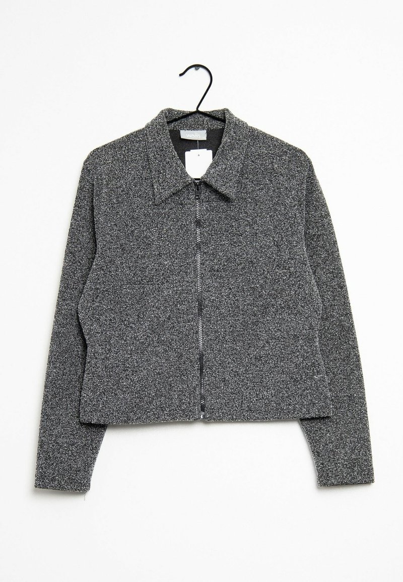 Veste zippée texturée grise avec col suspendue sur un cintre noir sur fond blanc.