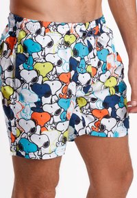 Bañadores coloridos con un estampado completo de personajes de Snoopy en colores vivos como azul, naranja y verde sobre un fondo blanco.