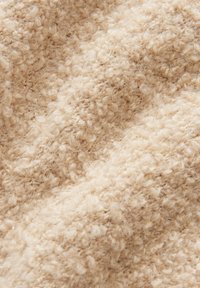 Tessuto beige testurizzato con un aspetto morbido e soffice, caratterizzato da una tessitura ad anelli e da un colore chiaro e neutro. Ideale per capi o accessori accoglienti.