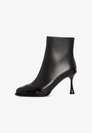 Crne gležnjače od glatke kože s sjajnim vrhom, s užim potpeticama i elegantnim, tijelu prianjajućim dizajnom.