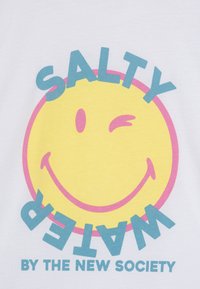 Hvit bomulls T-skjorte med et stort gult smilefjes som blunker, "SALTY" i blått over, og "WATER" i blått under, med rosa detaljer.