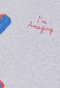 Maglietta grigia con una grafica blu e rossa di un personaggio, con il testo ricamato "Sono fantastico" in rosso. Materiale in cotone.
