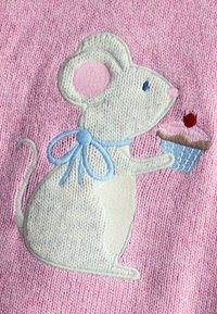 Bestickte Maus auf einem pinken Strickstoff, ausgestattet mit einer blauen Schleife, die einen Cupcake mit einer Kirsche obendrauf hält. Weiche Textur.