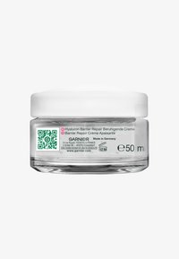 Przezroczysty szklany słoik zawierający 50 ml kremu z białą, gładką plastikową nakrętką. Etykieta zawiera tekst w wielu językach oraz kod QR.