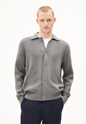 Gray ribbed cardigan with a notched collar, featuring a button closure, long sleeves, and a soft texture. Worn over a white shirt.