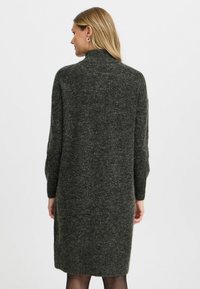 Abito lavorato a maglia di colore grigio scuro con colletto alto e maniche lunghe, realizzato in tessuto morbido e con texture, taglio di lunghezza media e design semplice.